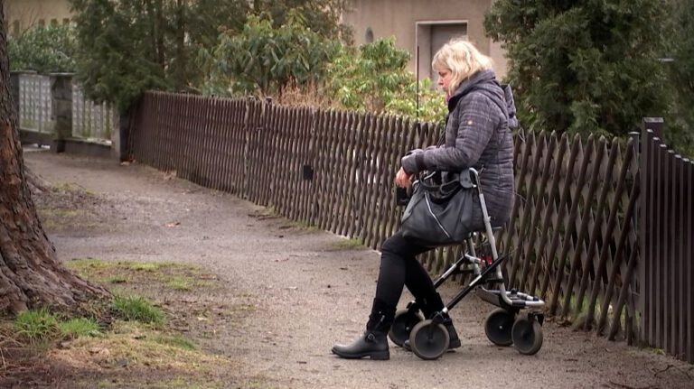 Frau im Rollator sitzt am Straßenrand